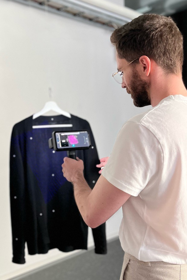 Researcher Jan Tepe directing a 3D scanner towards a shirt