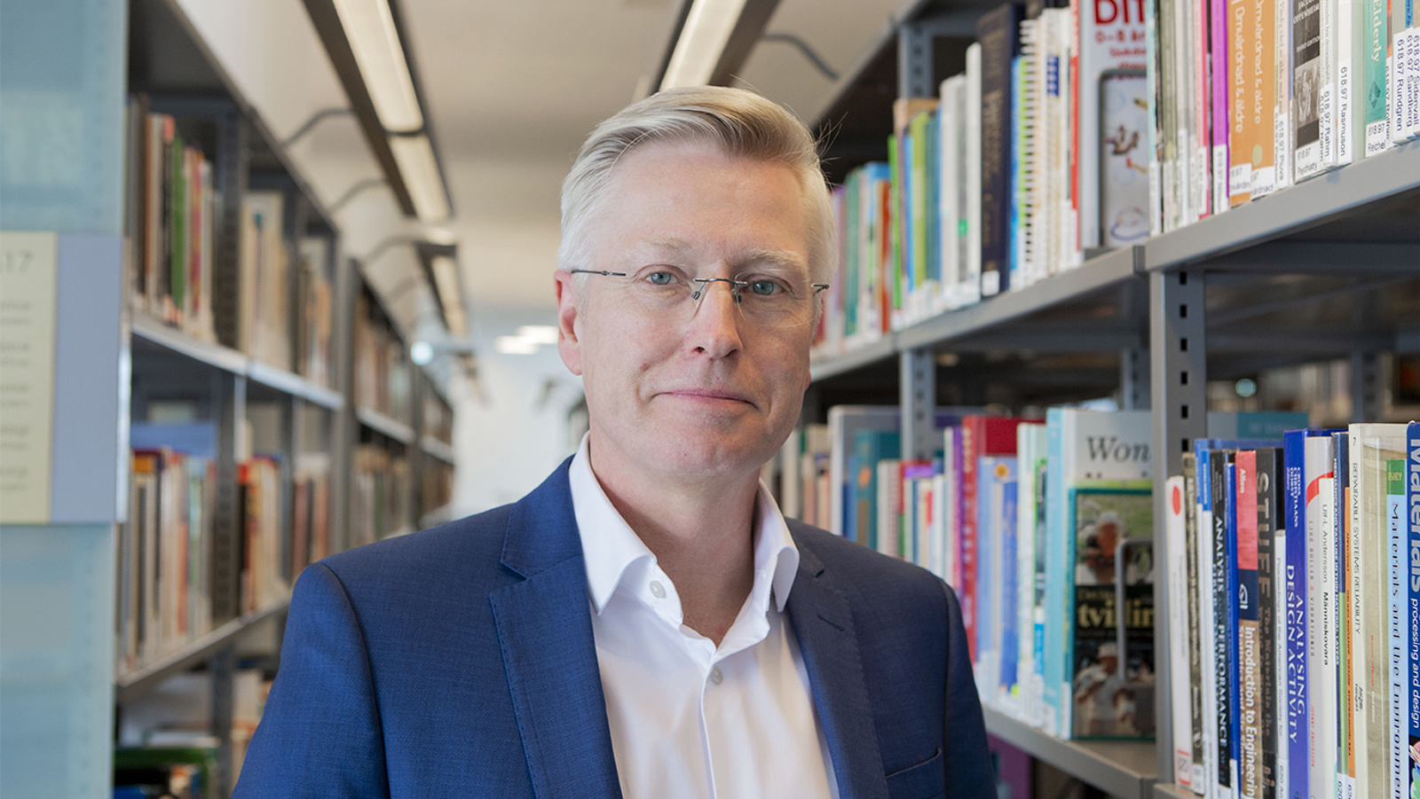 Gustaf Juell-Skielse framför bokhyllor i högskolans bibliotek. 