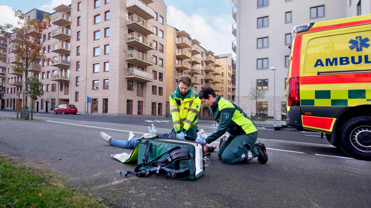 Ambulanspersonal gör livräddande insatser på en person som ligger på en gata.