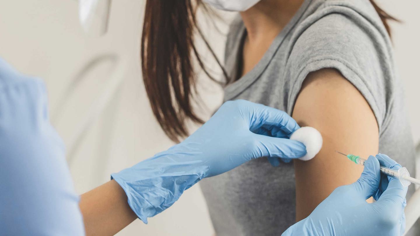 Sjuksköterska ger spruta i armen på patient