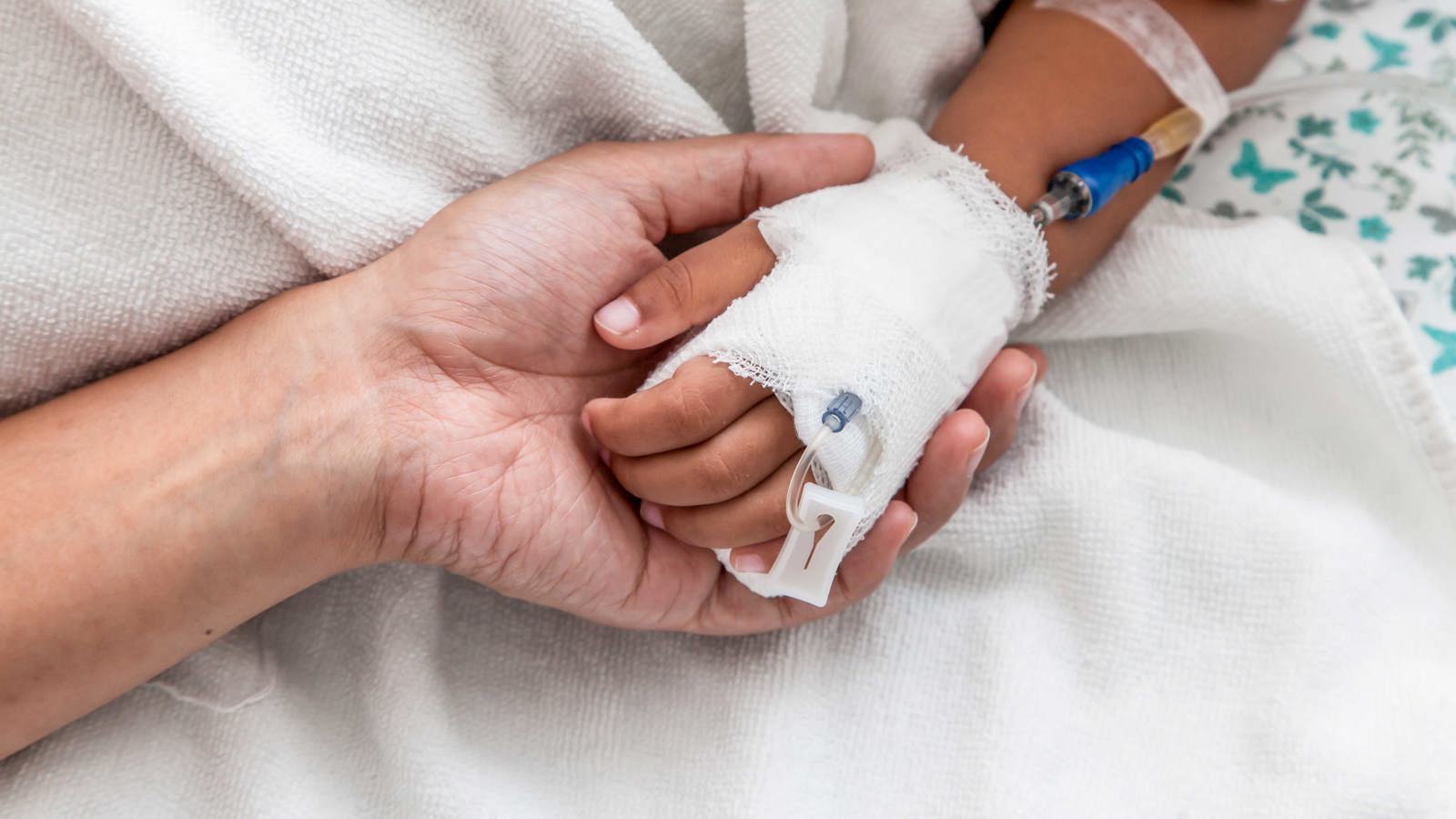 Vuxen håller barnhand i bandage