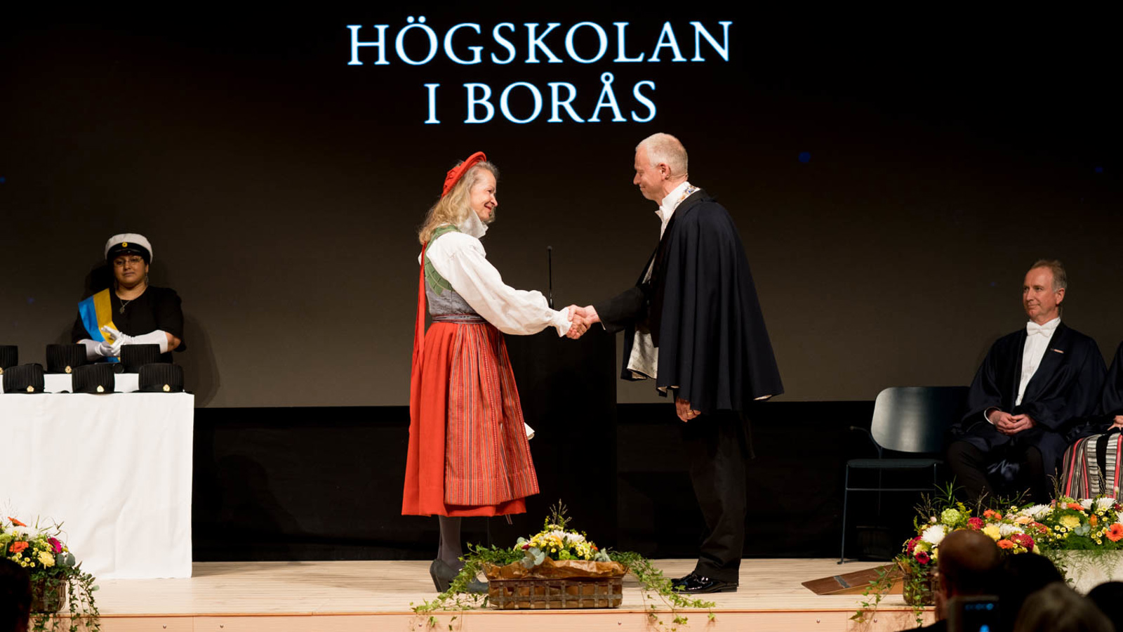Professor Carina Hermansson is shaking hands with Vice Chancellor Mats Tinnsten