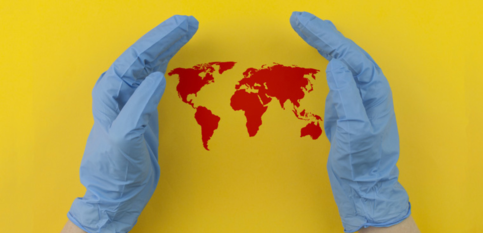Händer klädda i sterila handskar som håller om en världskarta