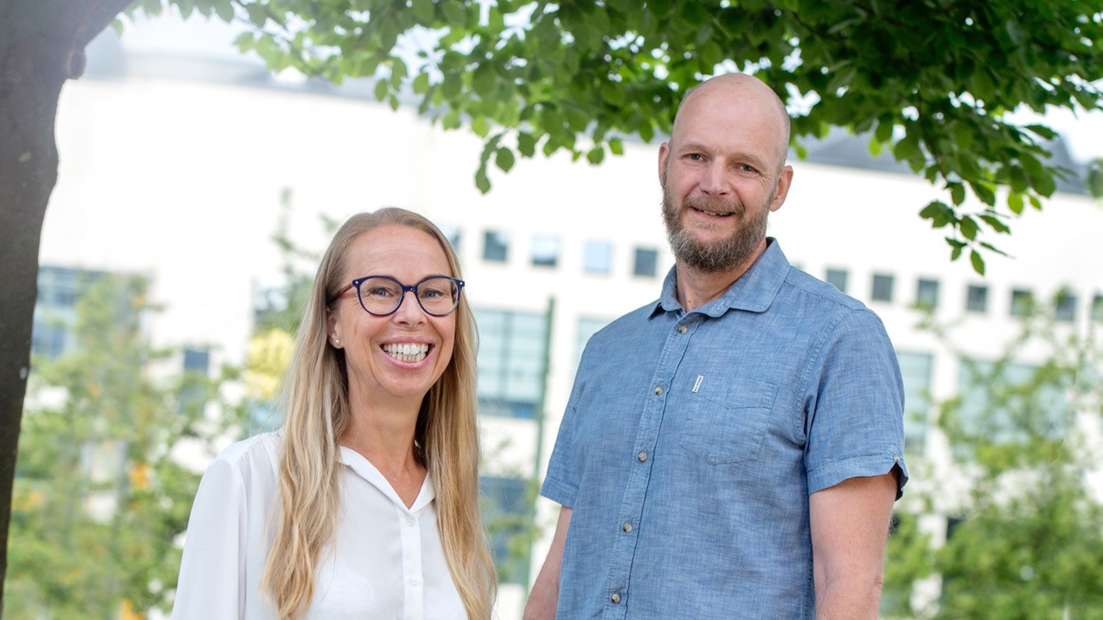 Marita Flisbäck och Magnus Andersson Hagiwara ler, fotograferade vid ett lummigt träd utanför högskolan. 