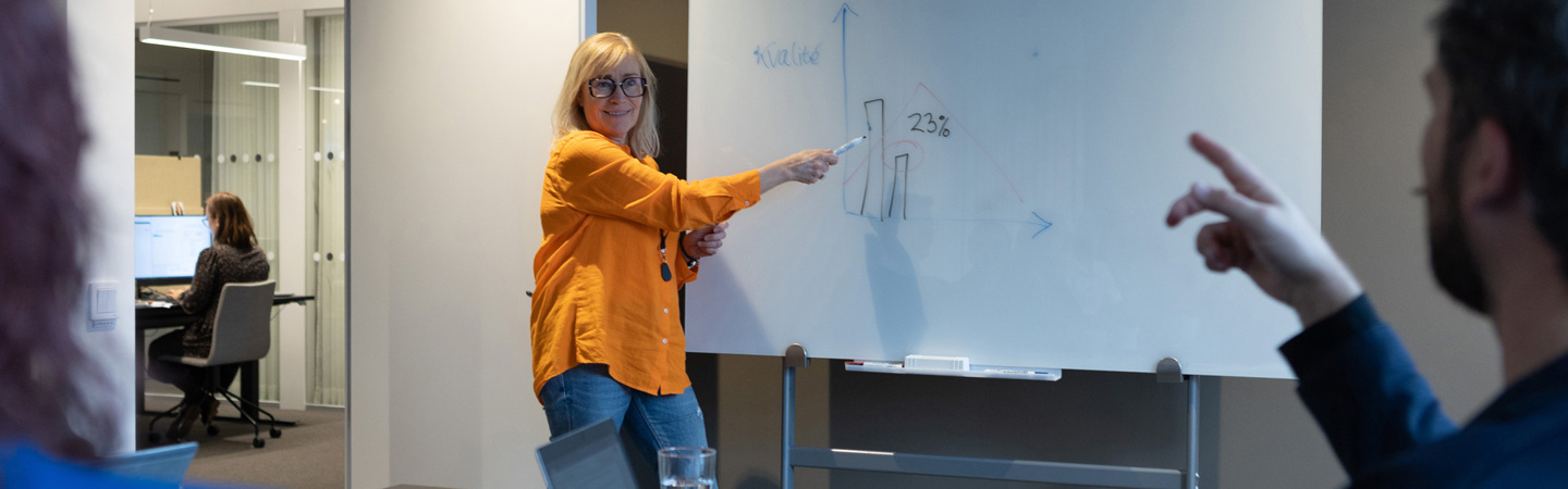 Person vid whiteboard håller möte