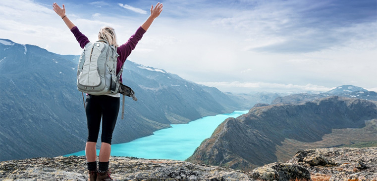 Bild på en person som står på en klippa med norska fjordar runt sig